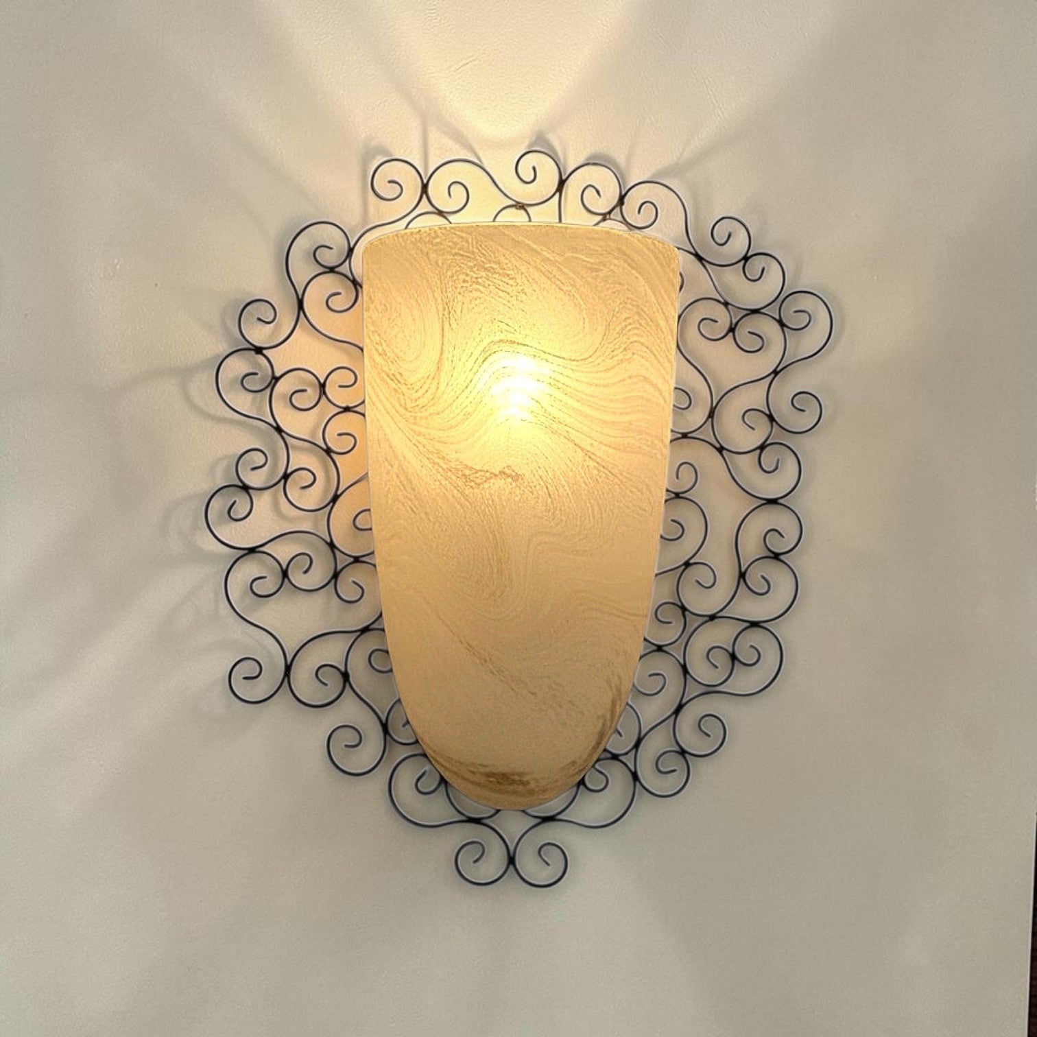 Wrought iron pocket wall sconces featuring a frosted amber glass / metal frame
